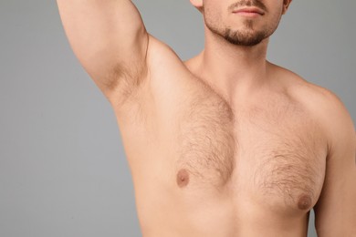 Photo of Young man showing hairy armpit on light grey background, closeup. Epilation procedure