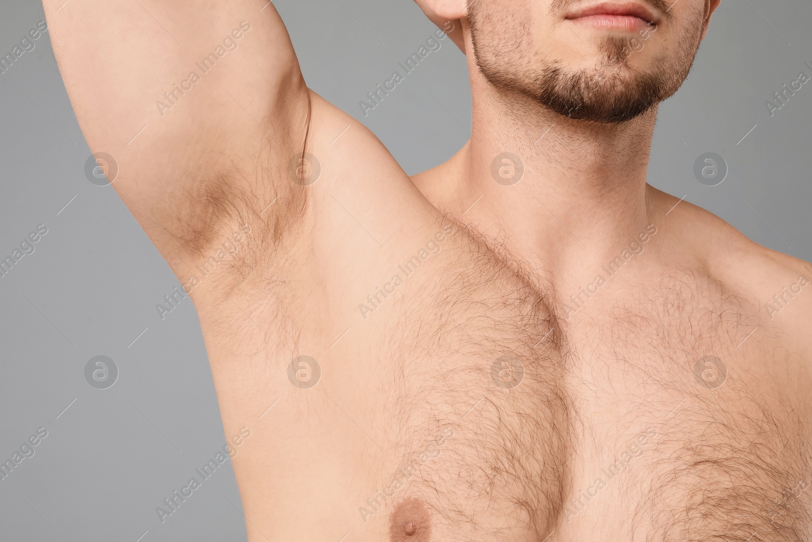 Young man showing hairy armpit on light grey background, closeup. Epilation procedure Photo of Young man showing hairy armpit on light grey background, closeup. Epilation procedure