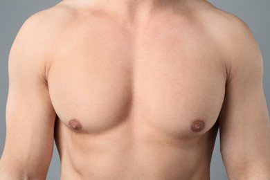 Photo of Young man with smooth chest after epilation procedure on light grey background, closeup
