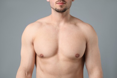 Photo of Young man with smooth chest after epilation procedure on light grey background, closeup