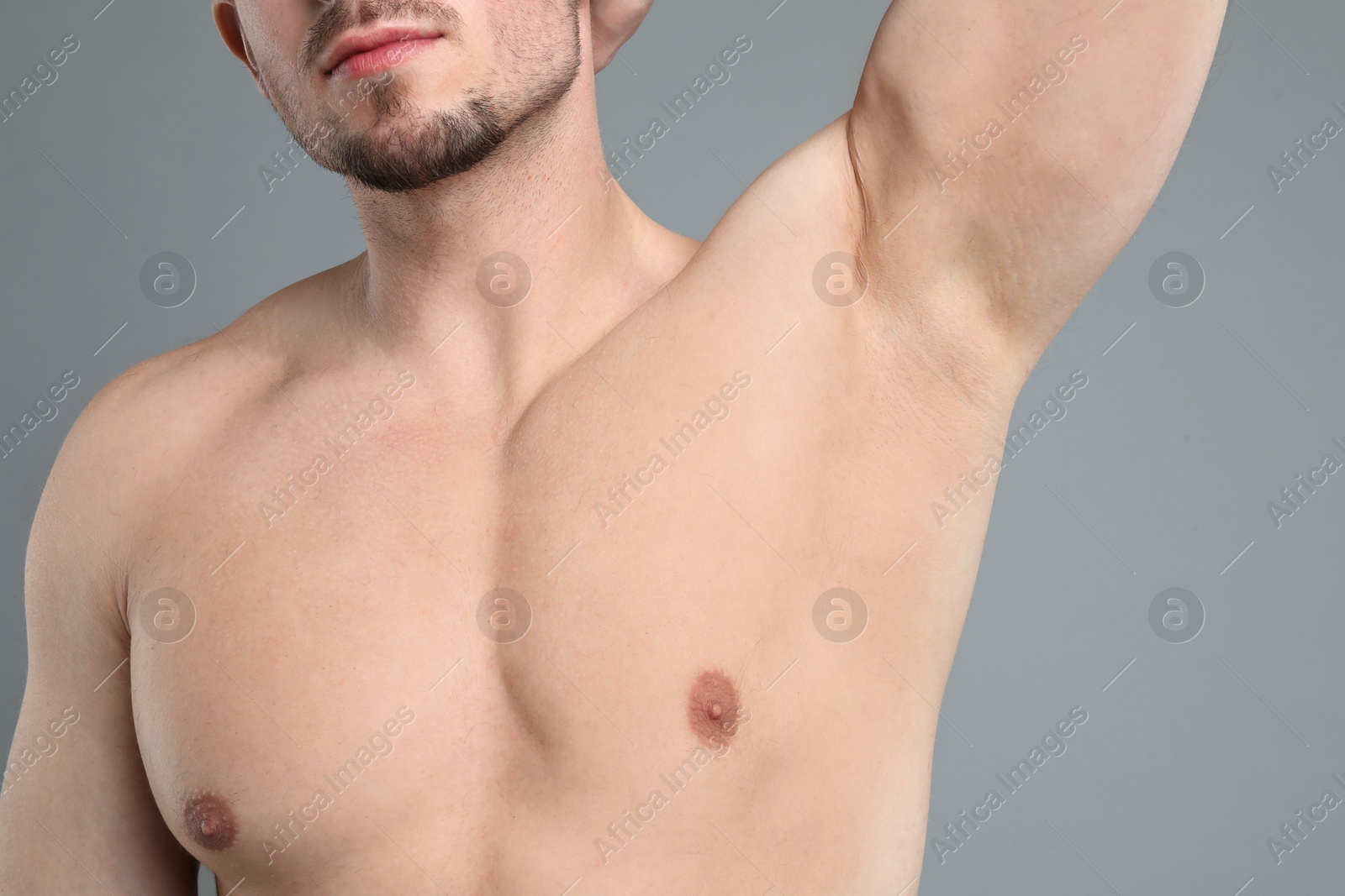 Young man showing smooth armpit after epilation procedure on light grey background, closeup Photo of Young man showing smooth armpit after epilation procedure on light grey background, closeup