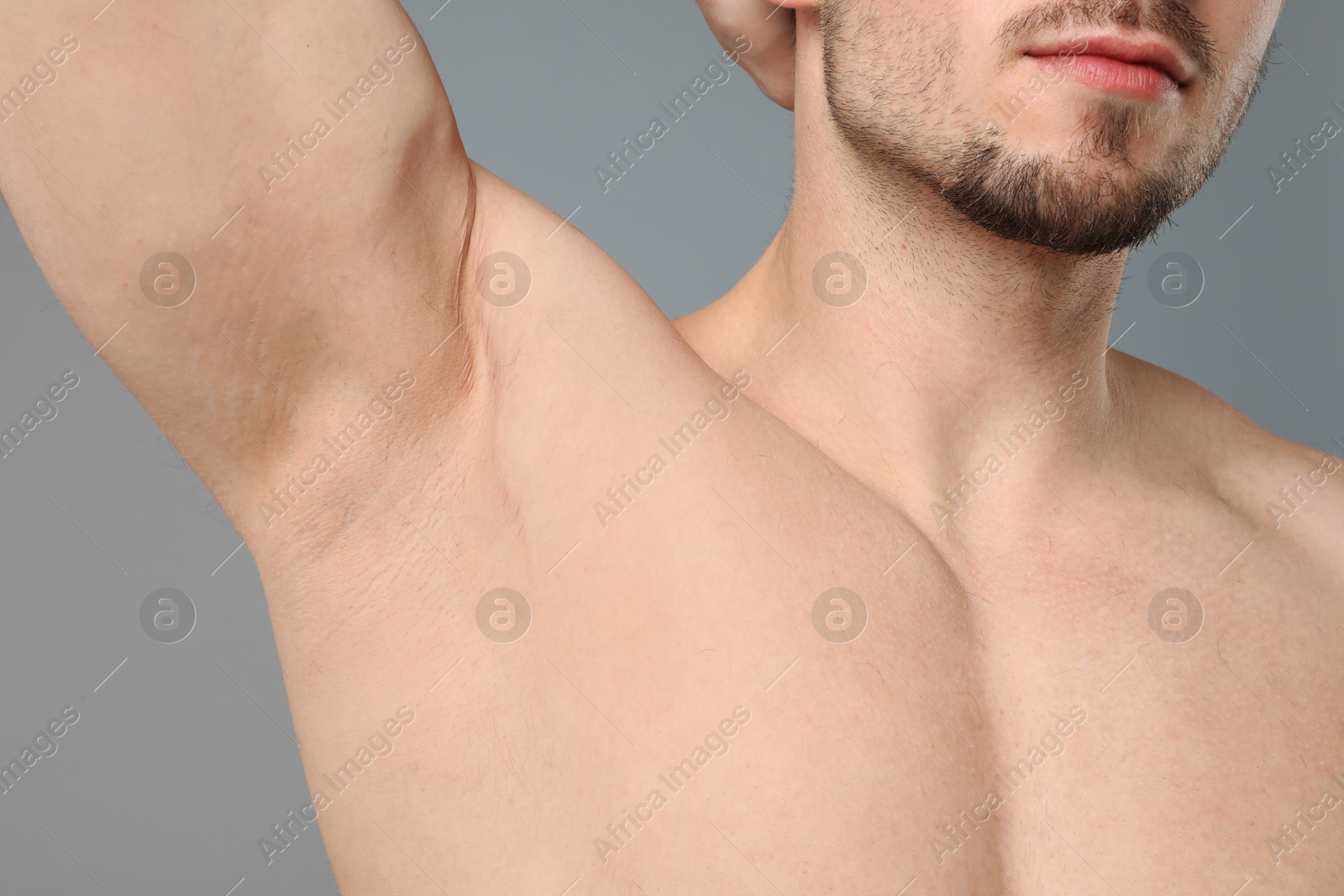 Young man showing smooth armpit after epilation procedure on light grey background, closeup Photo of Young man showing smooth armpit after epilation procedure on light grey background, closeup
