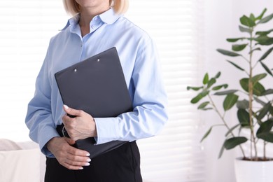 Photo of Professional psychologist with clipboard in office, closeup. Space for text