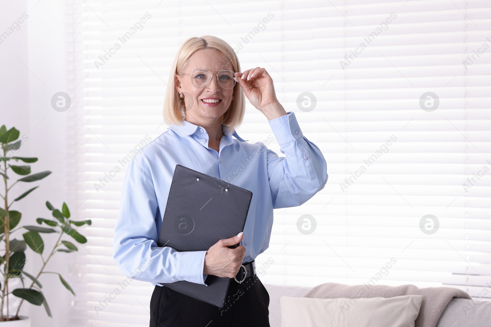 Professional psychologist in glasses with clipboard indoors Photo of Professional psychologist in glasses with clipboard indoors