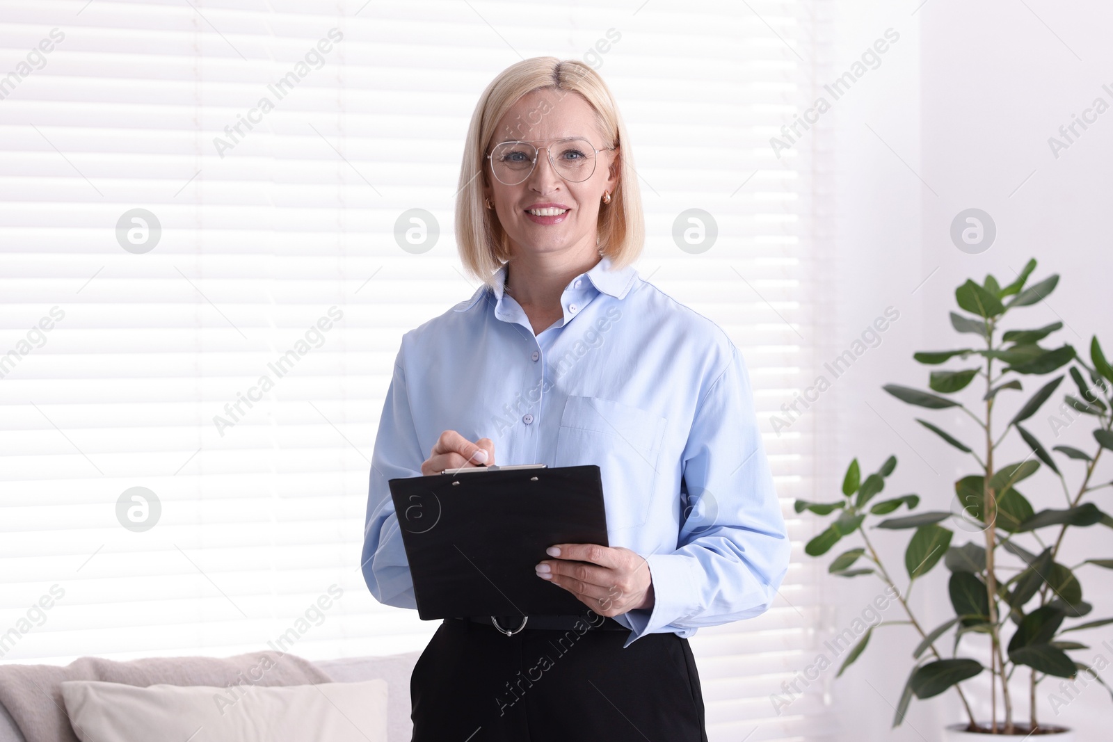 Professional psychologist in glasses with clipboard indoors Photo of Professional psychologist in glasses with clipboard indoors