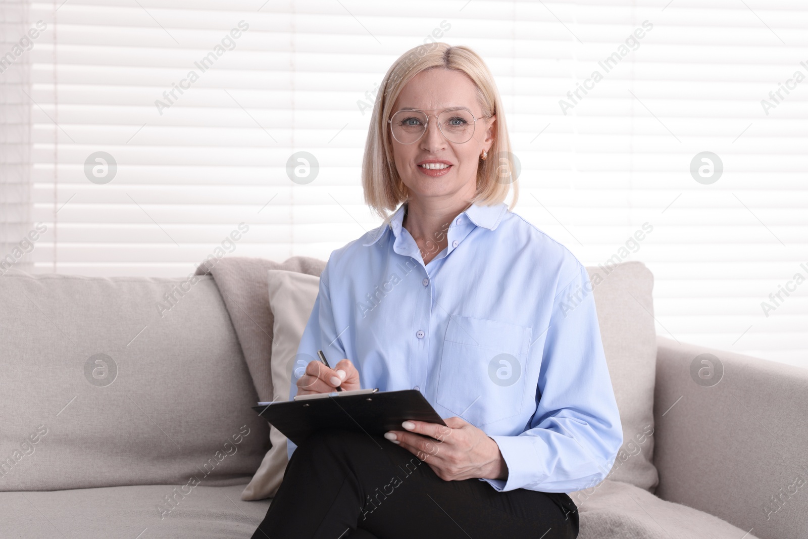 Professional psychologist with clipboard on sofa in office Photo of Professional psychologist with clipboard on sofa in office