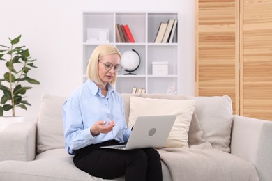 Photo of Professional psychologist with laptop on sofa in office