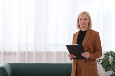 Photo of Professional psychologist with clipboard in office, space for text