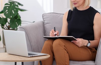Photo of Professional psychologist taking notes while working with laptop in office, closeup