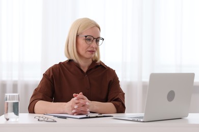 Photo of Professional psychologist working with laptop at table in office