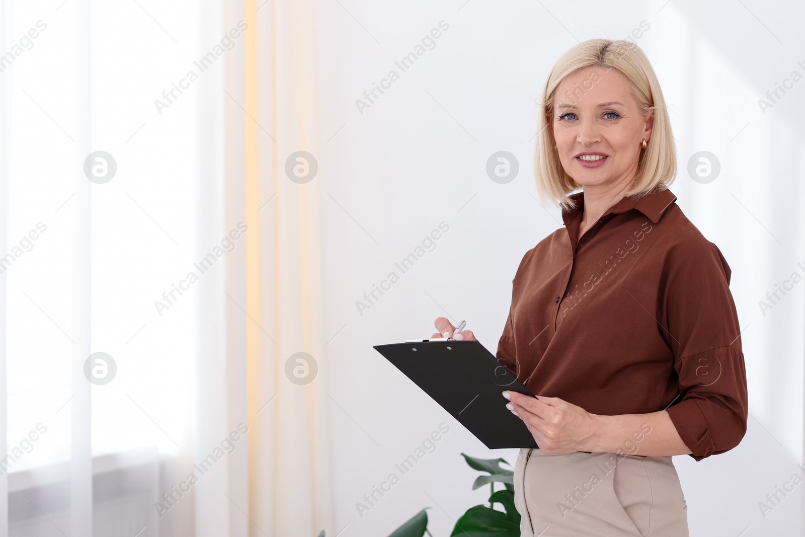 Professional psychologist with clipboard in office, space for text Photo of Professional psychologist with clipboard in office, space for text