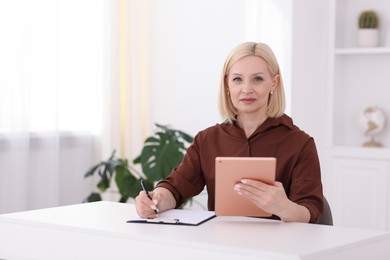 Photo of Professional psychologist with tablet taking notes at table in office, space for text