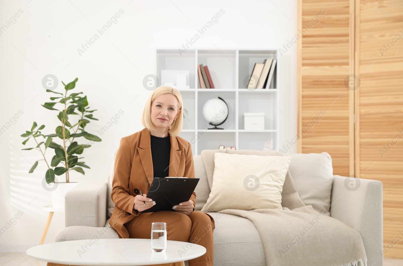 Professional psychologist with clipboard on sofa in office Photo of Professional psychologist with clipboard on sofa in office