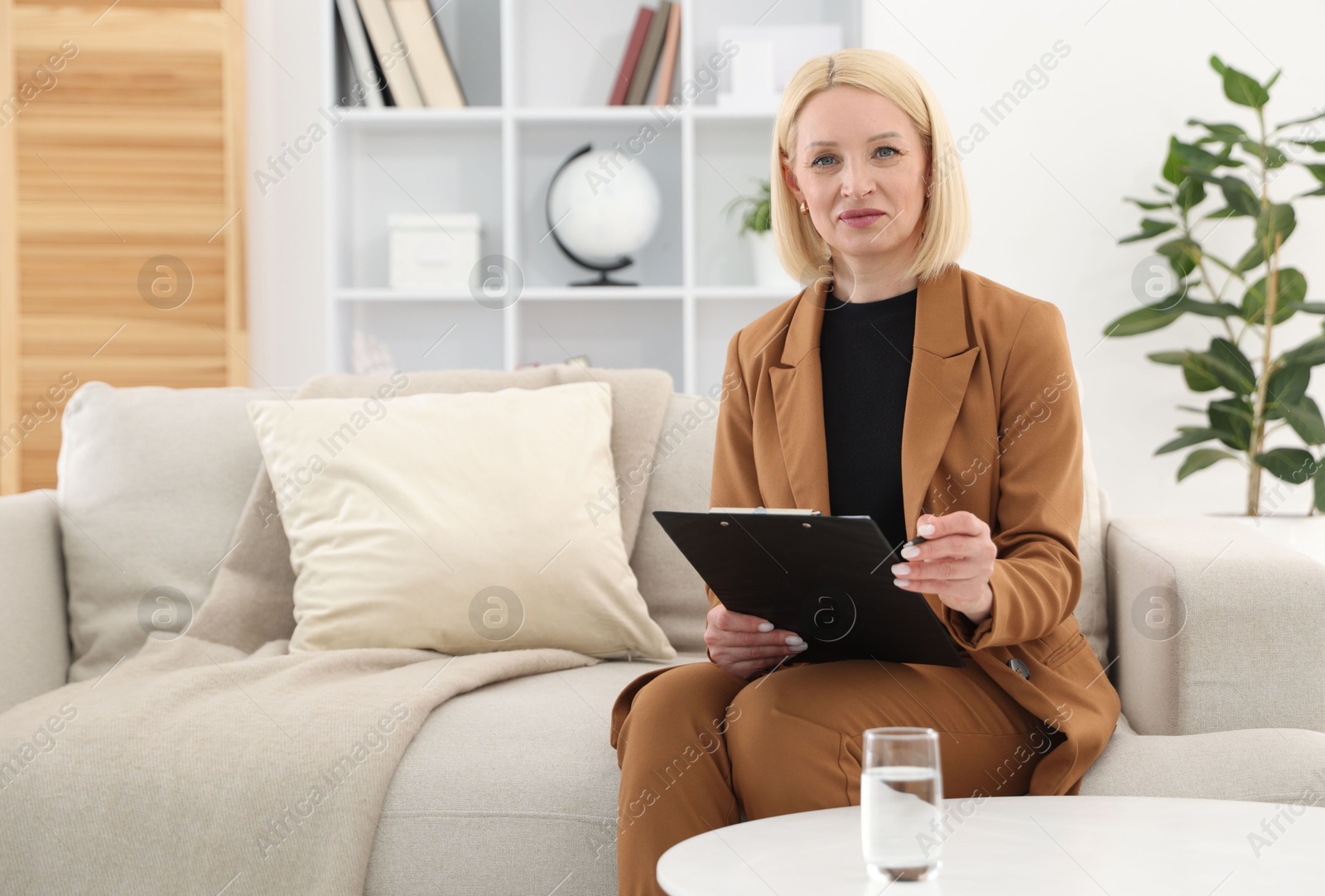Professional psychologist with clipboard on sofa in office Photo of Professional psychologist with clipboard on sofa in office