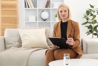 Photo of Professional psychologist with clipboard on sofa in office