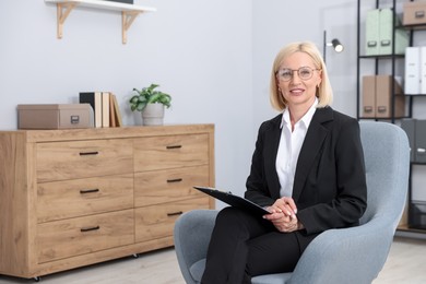 Photo of Professional psychologist with clipboard in armchair indoors, space for text