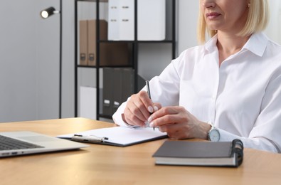 Photo of Professional psychologist taking notes at table in office, closeup