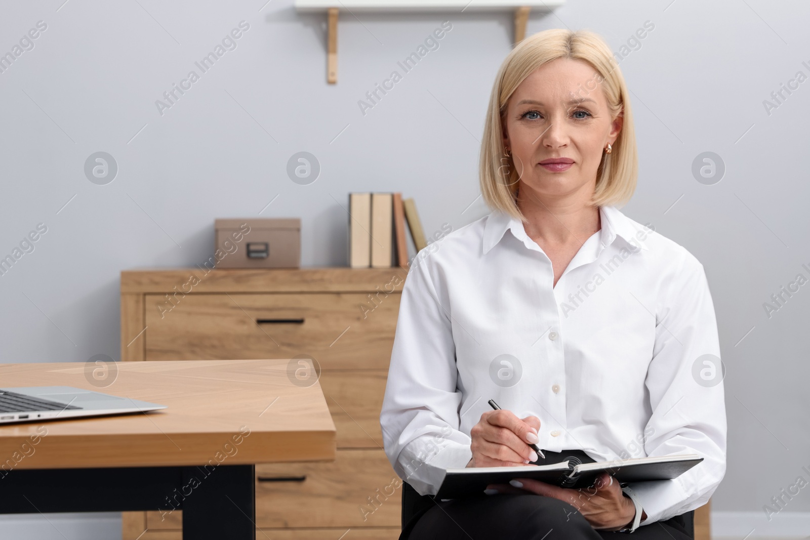Professional psychologist taking notes near table in office Photo of Professional psychologist taking notes near table in office