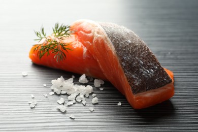 Photo of Seafood. Pieces of salmon fillet and spices on black wooden table, closeup