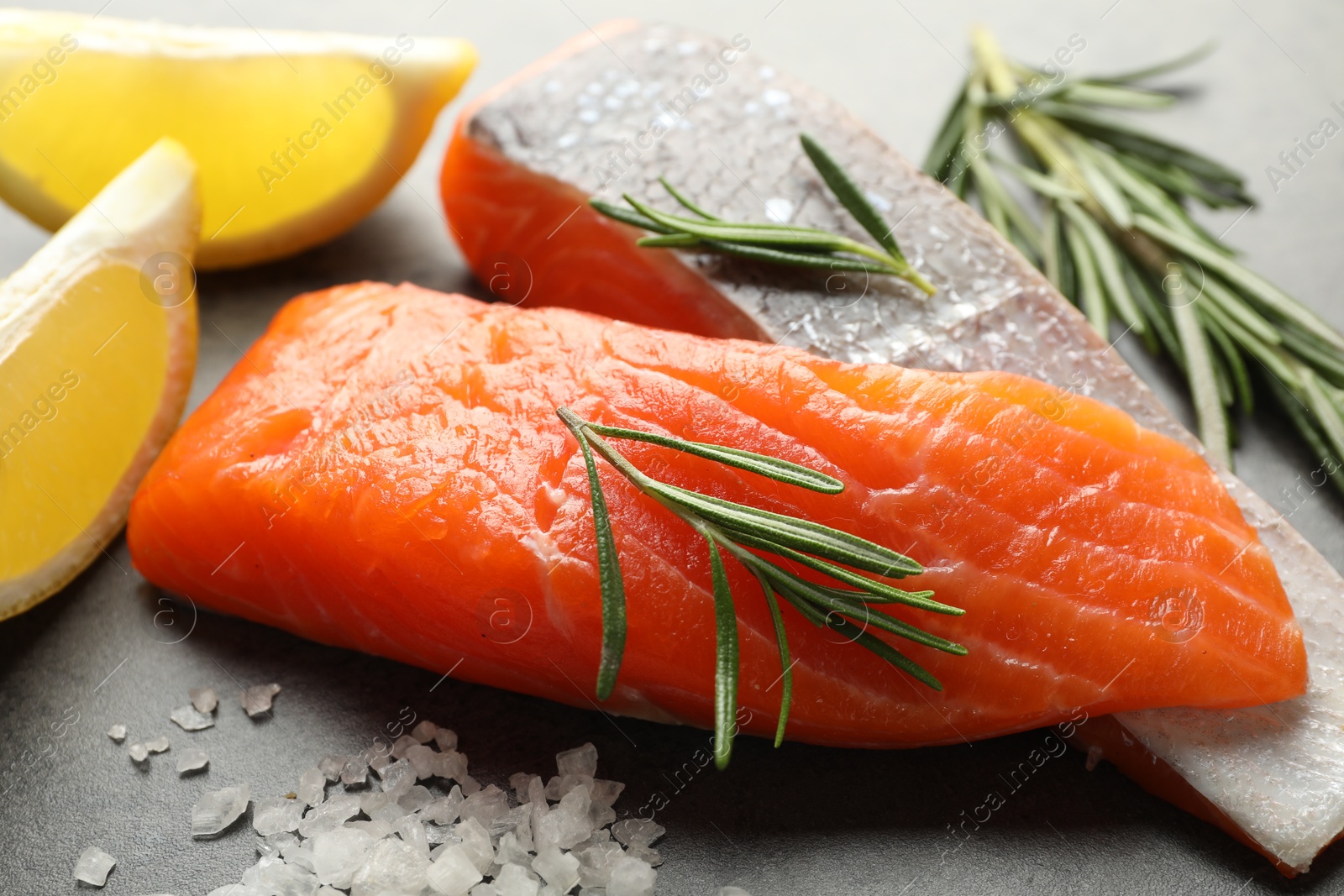 Seafood. Pieces of salmon fillet, spices and lemon wedges on gray table, closeup Photo of Seafood. Pieces of salmon fillet, spices and lemon wedges on gray table, closeup