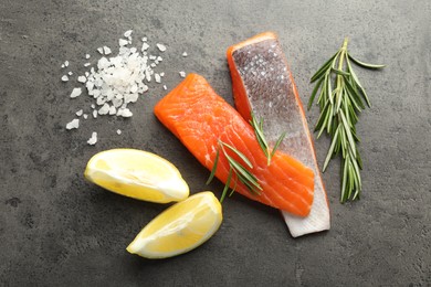 Photo of Seafood. Pieces of salmon fillet, spices and lemon wedges on gray textured table, flat lay