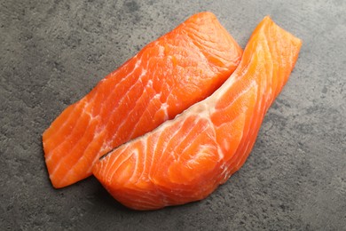 Photo of Seafood. Pieces of salmon fillet on gray textured table, top view