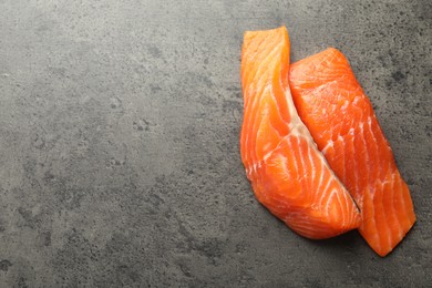 Photo of Seafood. Pieces of salmon fillet on gray textured table, top view. Space for text