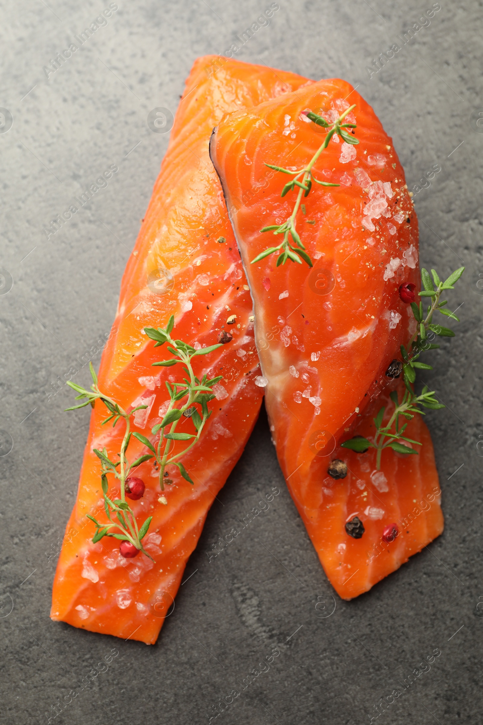 Seafood. Pieces of salmon fillet with spices on gray textured table, top view Photo of Seafood. Pieces of salmon fillet with spices on gray textured table, top view