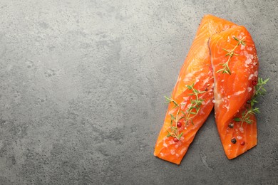 Photo of Seafood. Pieces of salmon fillet with spices on gray textured table, top view. Space for text