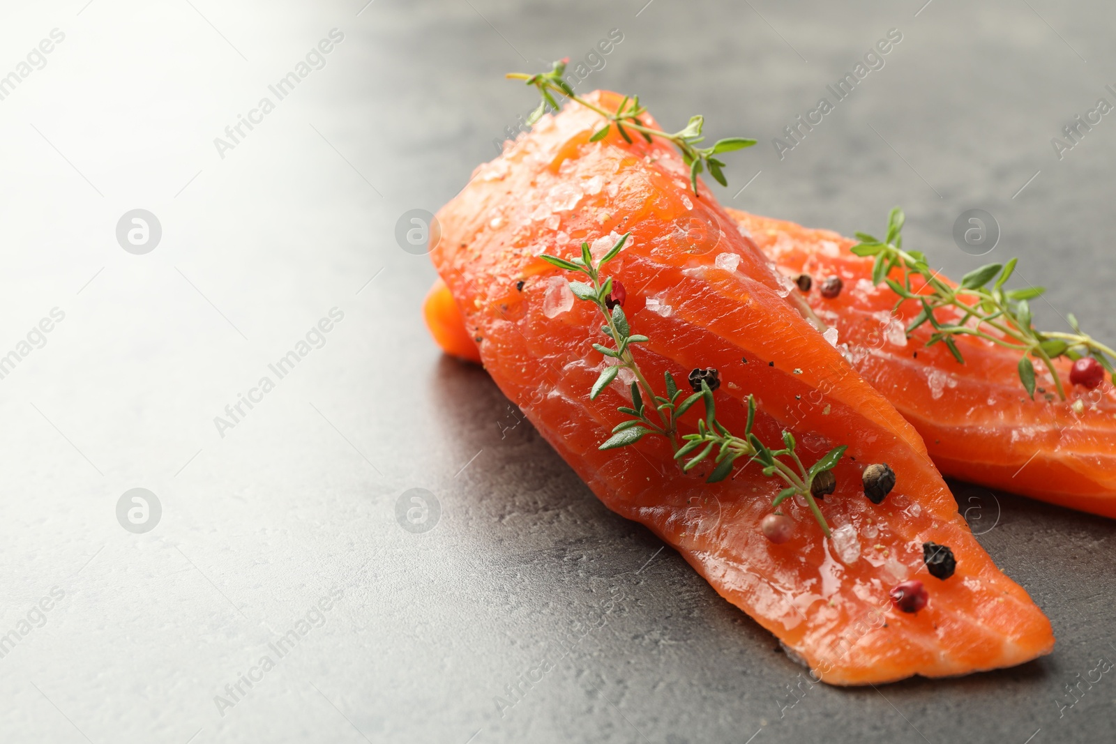 Seafood. Pieces of salmon fillet with spices on gray table, closeup. Space for text Photo of Seafood. Pieces of salmon fillet with spices on gray table, closeup. Space for text