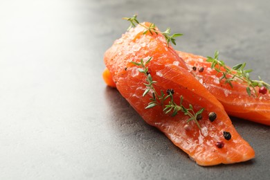 Photo of Seafood. Pieces of salmon fillet with spices on gray table, closeup. Space for text