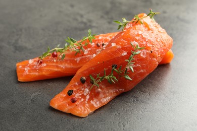 Photo of Seafood. Pieces of salmon fillet with spices on gray textured table, closeup
