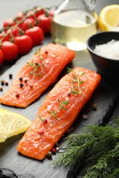 Photo of Seafood. Pieces of salmon fillet, spices, tomatoes and oil on table, closeup