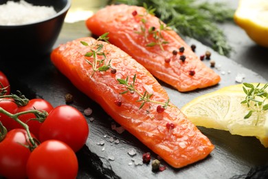 Photo of Seafood. Pieces of salmon fillet, spices, tomatoes and lemon on table, closeup