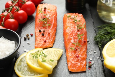 Photo of Seafood. Pieces of salmon fillet, spices, tomatoes and lemon slices on table, closeup