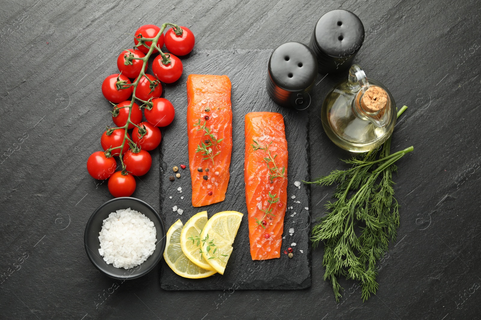 Seafood. Pieces of salmon fillet, spices, tomatoes, oil and lemon slices on black textured table, flat lay Photo of Seafood. Pieces of salmon fillet, spices, tomatoes, oil and lemon slices on black textured table, flat lay