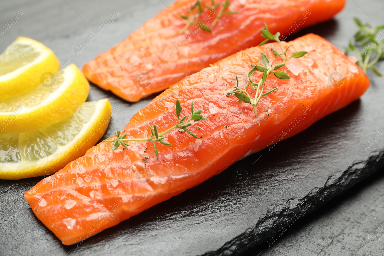 Seafood. Pieces of salmon fillet, thyme and lemon slices on table, closeup Photo of Seafood. Pieces of salmon fillet, thyme and lemon slices on table, closeup