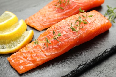 Photo of Seafood. Pieces of salmon fillet, thyme and lemon slices on table, closeup