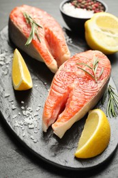 Photo of Seafood. Salmon steaks, spices and lemon wedges on black table, closeup