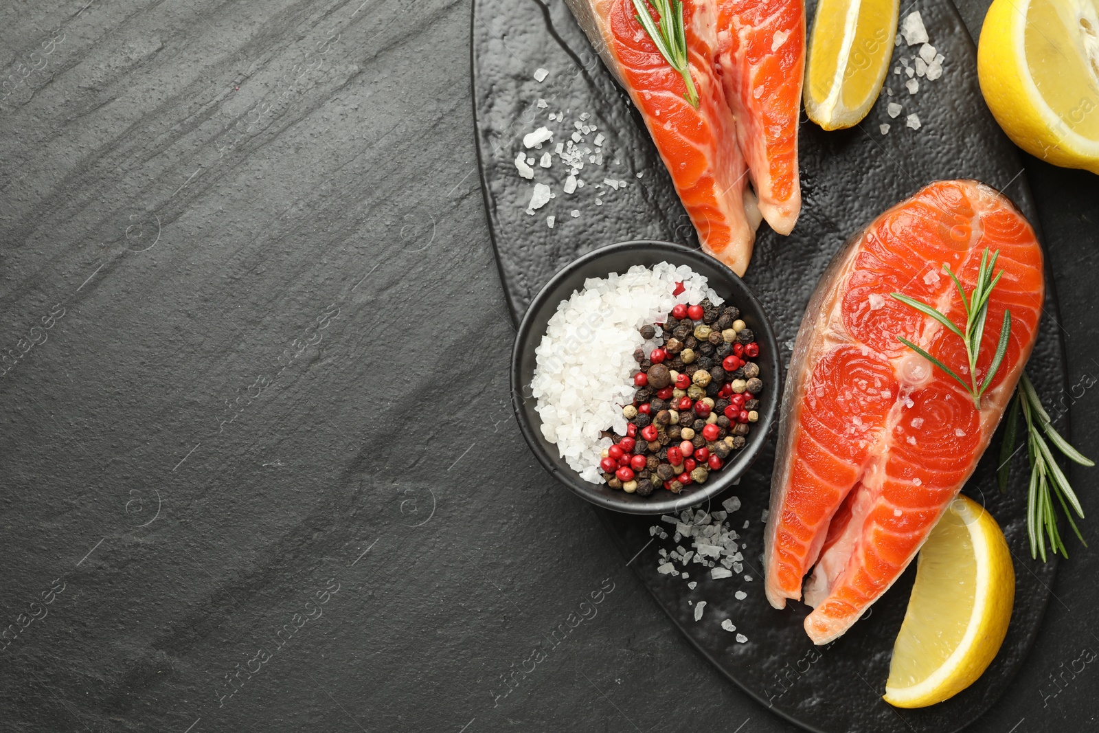 Seafood. Salmon steaks, spices and lemon on black textured table, top view. Space for text Photo of Seafood. Salmon steaks, spices and lemon on black textured table, top view. Space for text