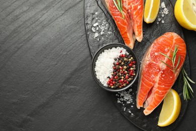 Photo of Seafood. Salmon steaks, spices and lemon on black textured table, top view. Space for text