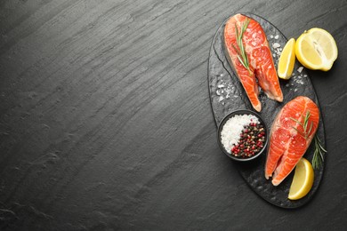 Photo of Seafood. Salmon steaks, spices and lemon on black textured table, top view. Space for text