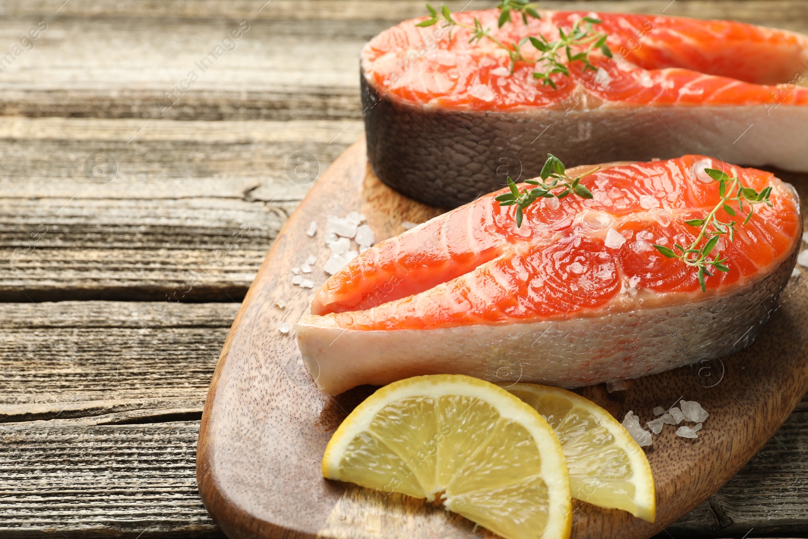 Seafood. Salmon steaks, spices and lemon slices on wooden table, closeup. Space for text Photo of Seafood. Salmon steaks, spices and lemon slices on wooden table, closeup. Space for text