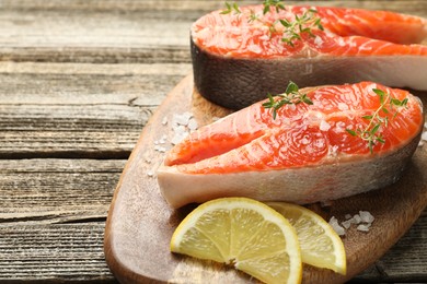 Photo of Seafood. Salmon steaks, spices and lemon slices on wooden table, closeup. Space for text