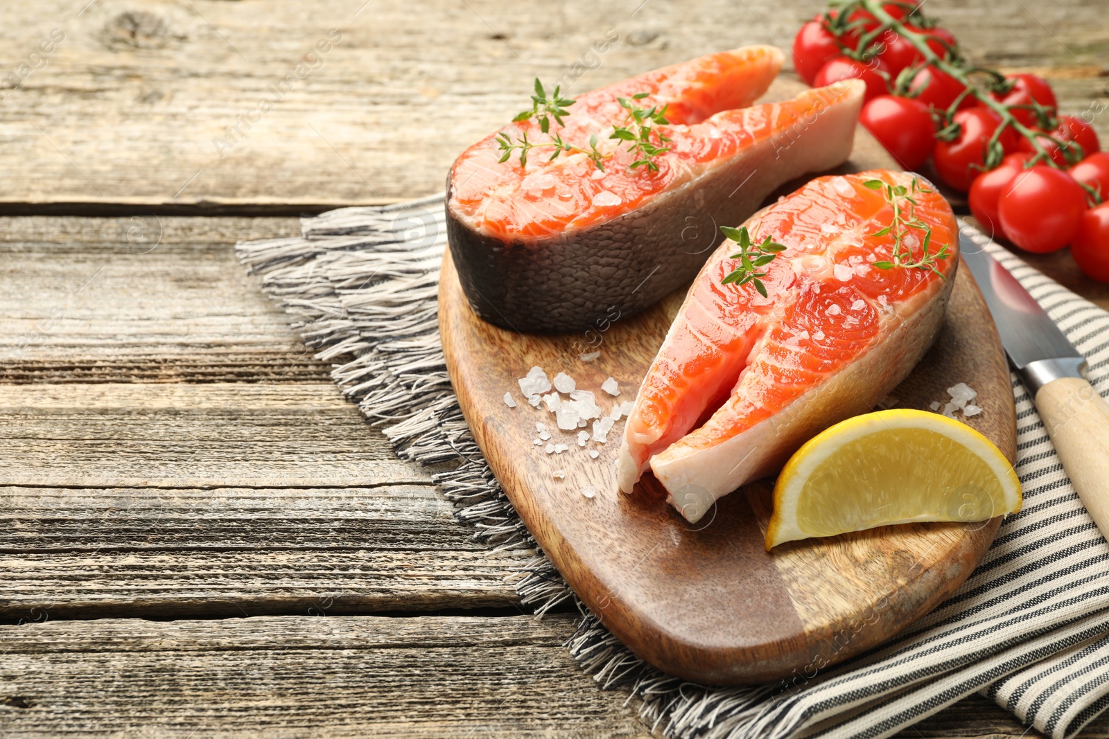 Seafood. Salmon steaks, spices, lemon wedge and tomatoes on wooden table, closeup. Space for text Photo of Seafood. Salmon steaks, spices, lemon wedge and tomatoes on wooden table, closeup. Space for text