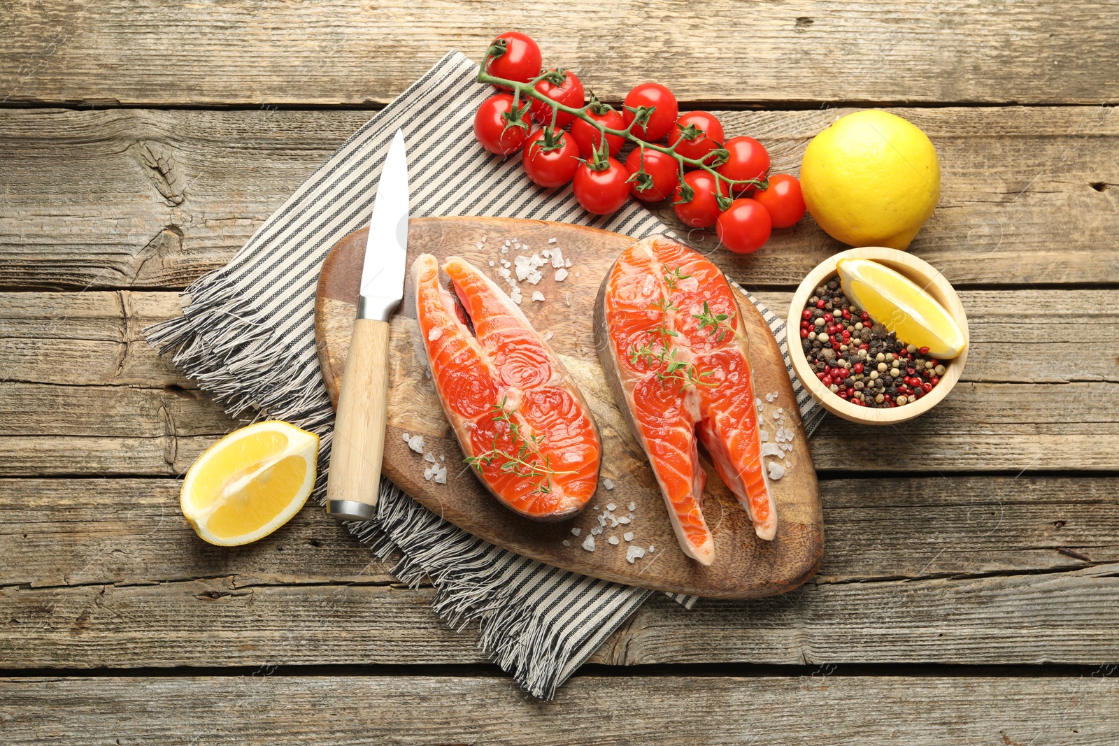 Seafood. Salmon steaks, spices, tomatoes, lemons and knife on wooden table, flat lay Photo of Seafood. Salmon steaks, spices, tomatoes, lemons and knife on wooden table, flat lay