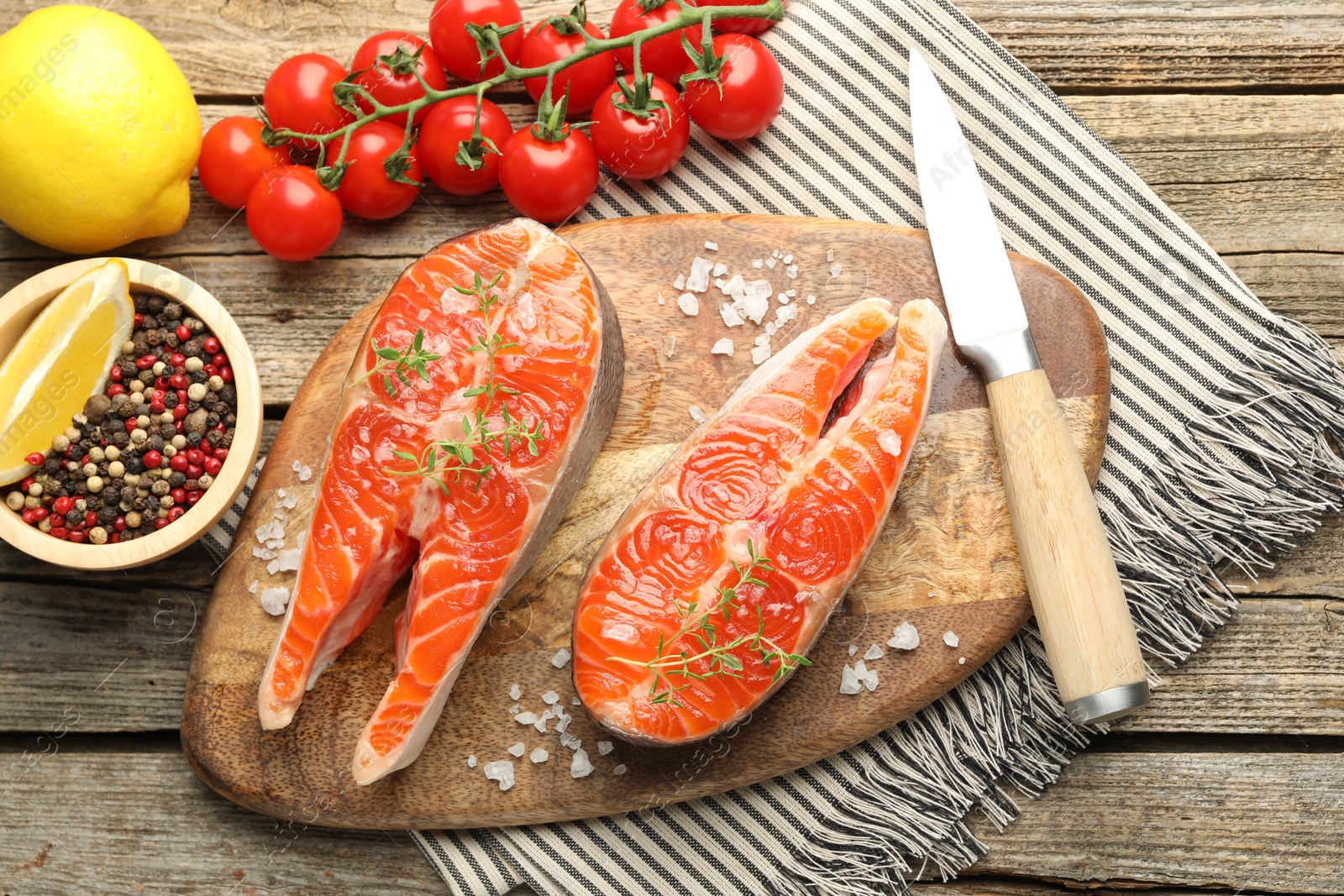 Seafood. Salmon steaks, spices, tomatoes, lemons and knife on wooden table, flat lay Photo of Seafood. Salmon steaks, spices, tomatoes, lemons and knife on wooden table, flat lay