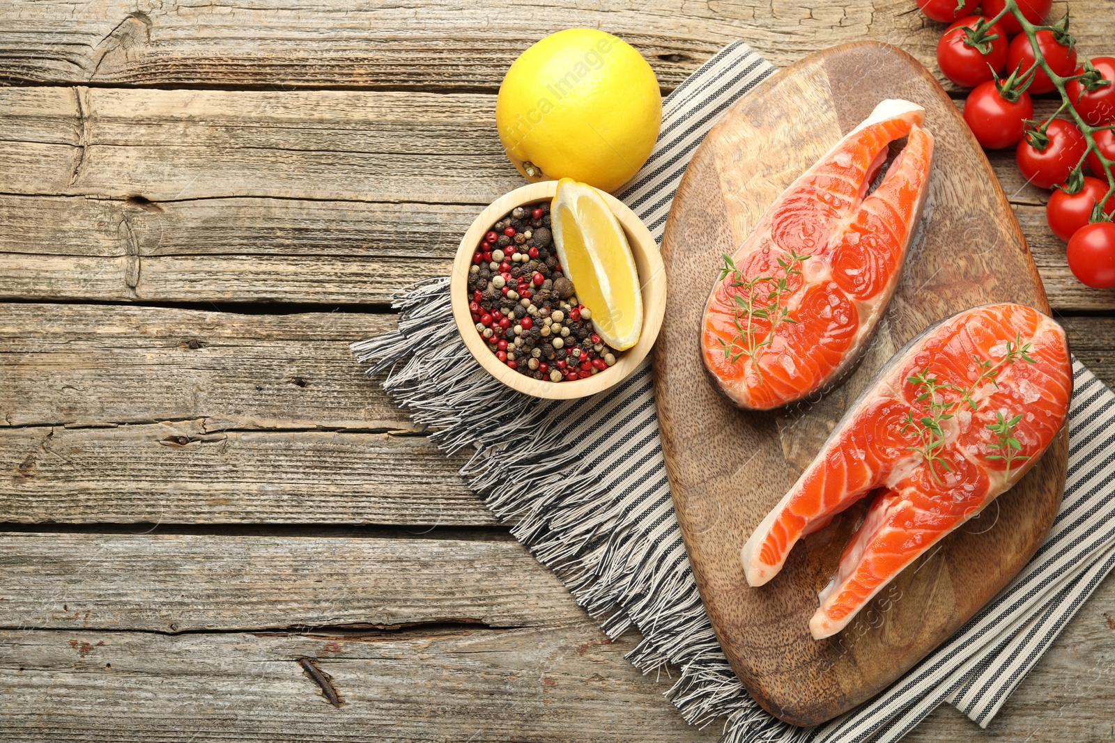 Seafood. Salmon steaks, spices, tomatoes and lemons on wooden table, flat lay. Space for text Photo of Seafood. Salmon steaks, spices, tomatoes and lemons on wooden table, flat lay. Space for text