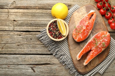 Photo of Seafood. Salmon steaks, spices, tomatoes and lemons on wooden table, flat lay. Space for text
