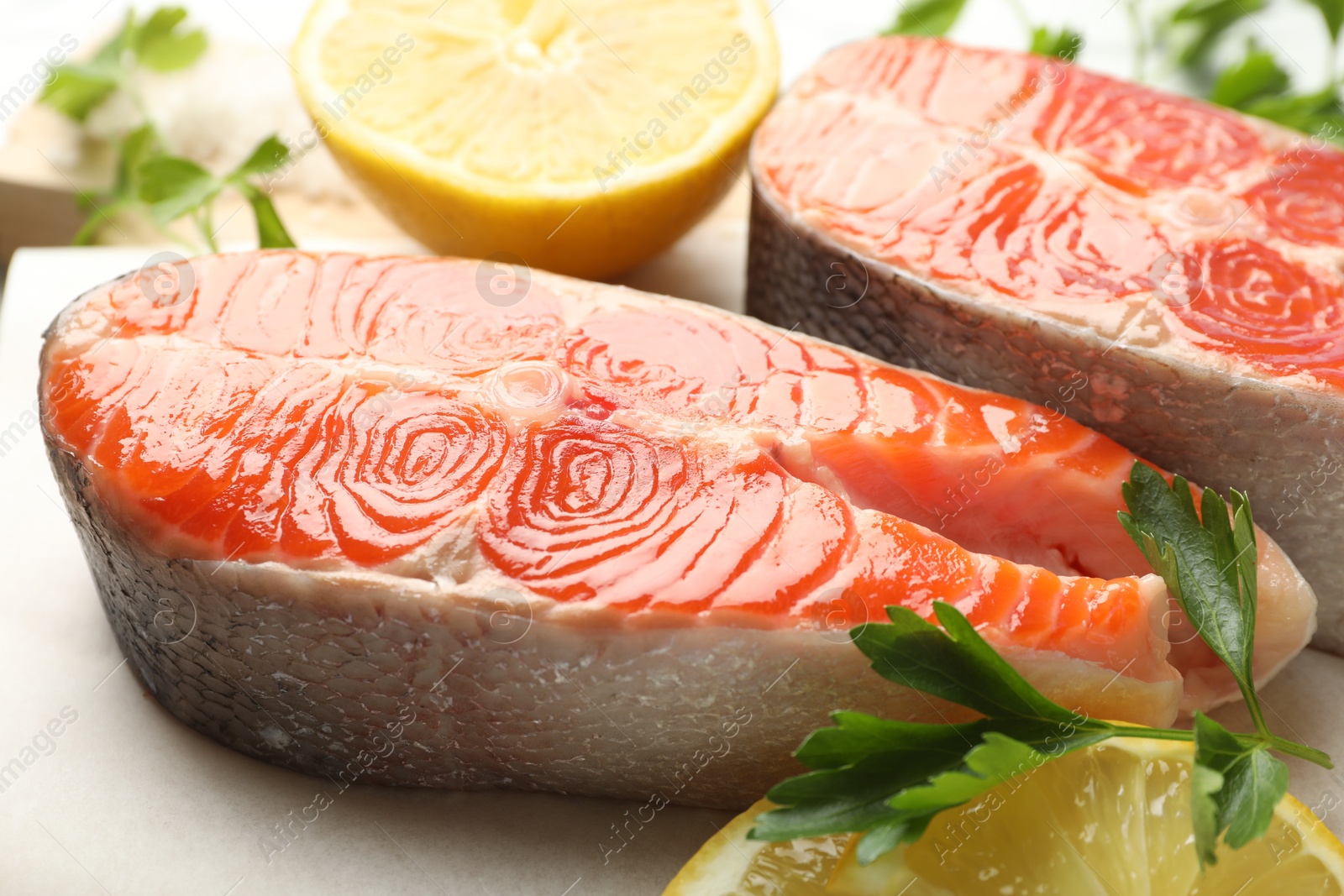 Seafood. Fresh raw salmon steaks, parsley and pieces of lemon on table, closeup Photo of Seafood. Fresh raw salmon steaks, parsley and pieces of lemon on table, closeup